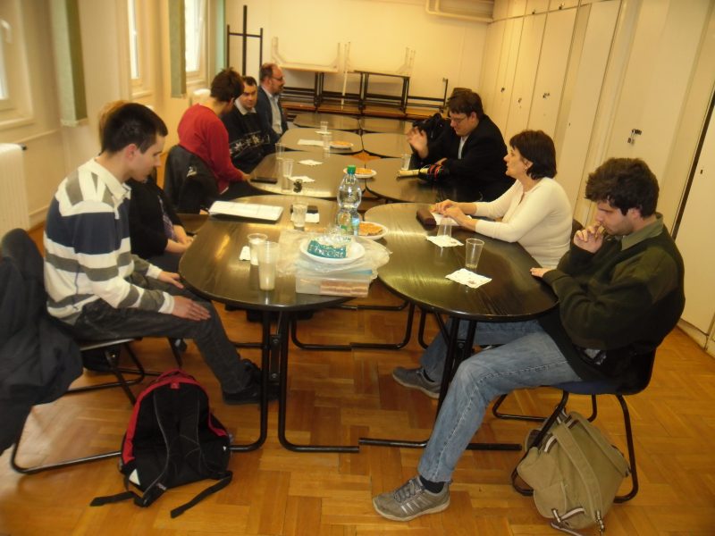 A képen a XVIII. kerületi tagok ülnek egy asztal körül és hallgatják Robit, a klub szervezőjét