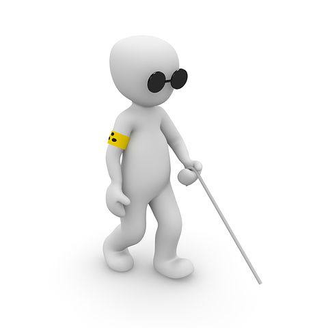 A képen egy napszemüveges, fehér bottal sétáló bábu látható