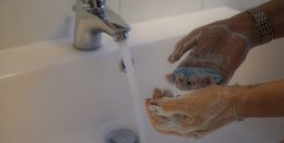 A képen egy fürdőszobai csapból folyó víz előtt egy besszappanozott kéz látható.