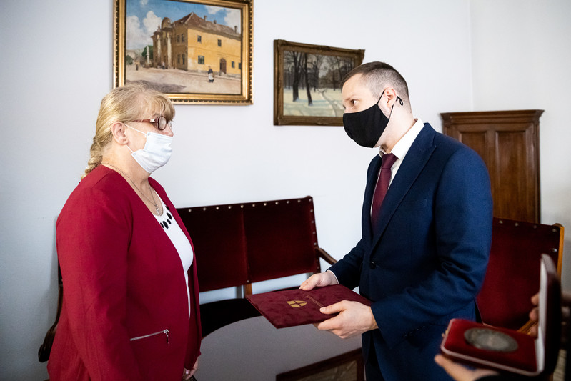 Soproni Tamás, Terézváros polgármestere átadja Erzsébetnek a kitüntetést: az érmet és az oklevelet.