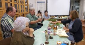 Az asztal körül a csoport tagjai és a múzeumpedagógus, az asztalon gyógy-és fűszernövények láthatók.