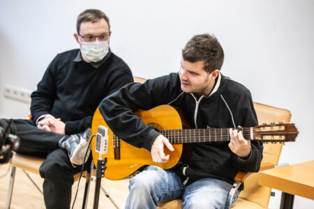 A két fellépő közelről látszik, Domoszlai János gitározik és énekel.