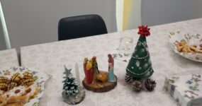 A képen az ünnepi asztalon lévő sütemények, kézzel készített karácsonyfák és egy jászol látszik.