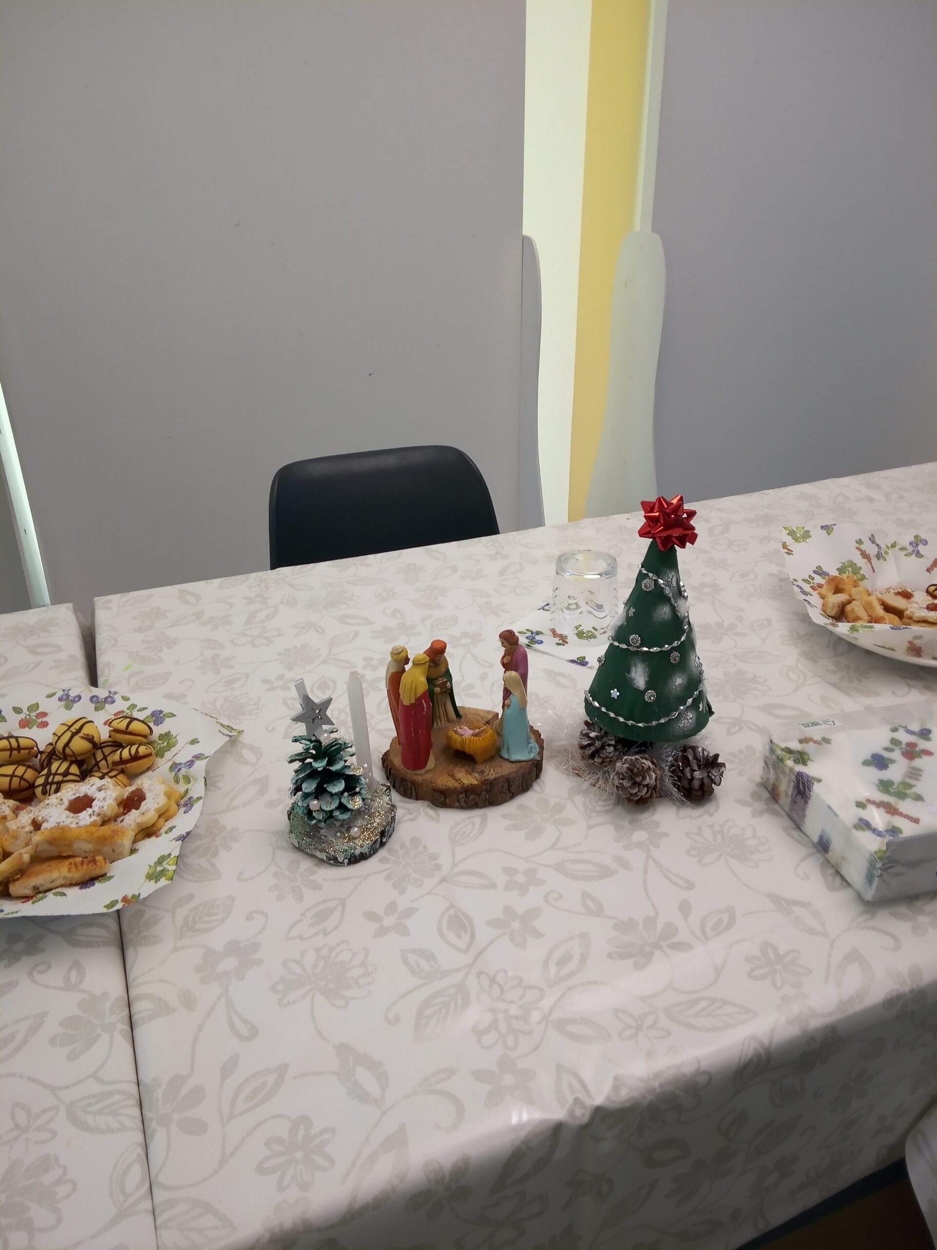 A képen az ünnepi asztalon lévő sütemények, kézzel készített karácsonyfák és egy jászol látszik.