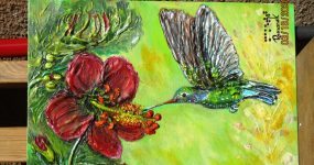 A képen a művésznő Makett című alkotása látható: egy hosszú csőrű kolibri repdes egy piros virág előtt. A festmény a helyszínen is megnézhető, megtapintható lesz.