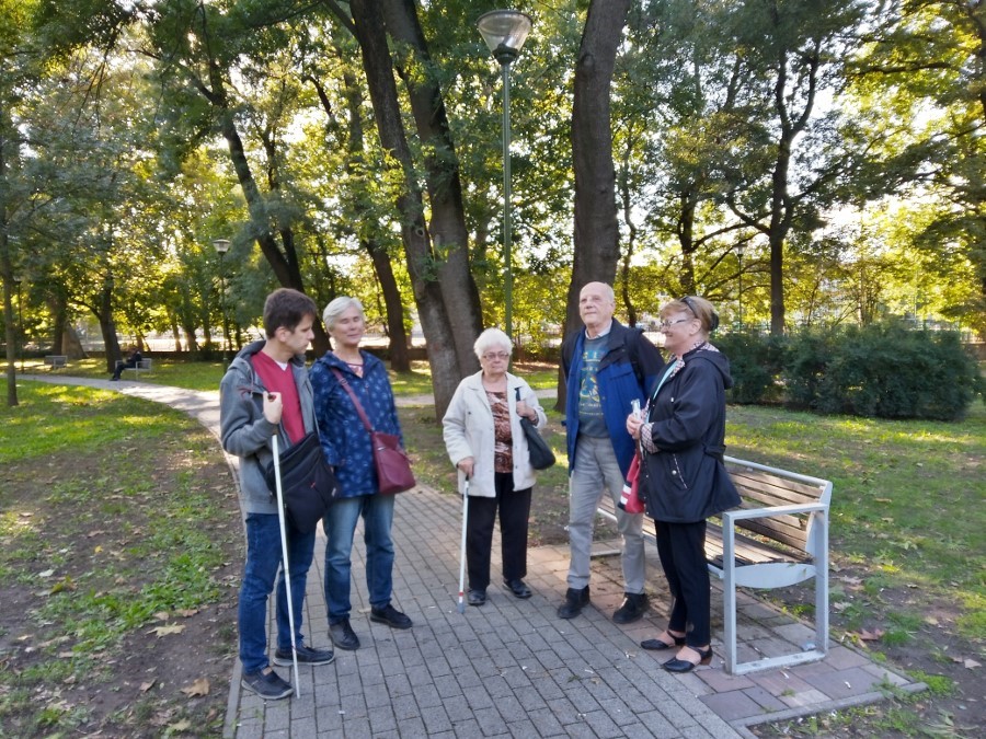 A tagok sétálnak és beszélgetnek a Népkertben.