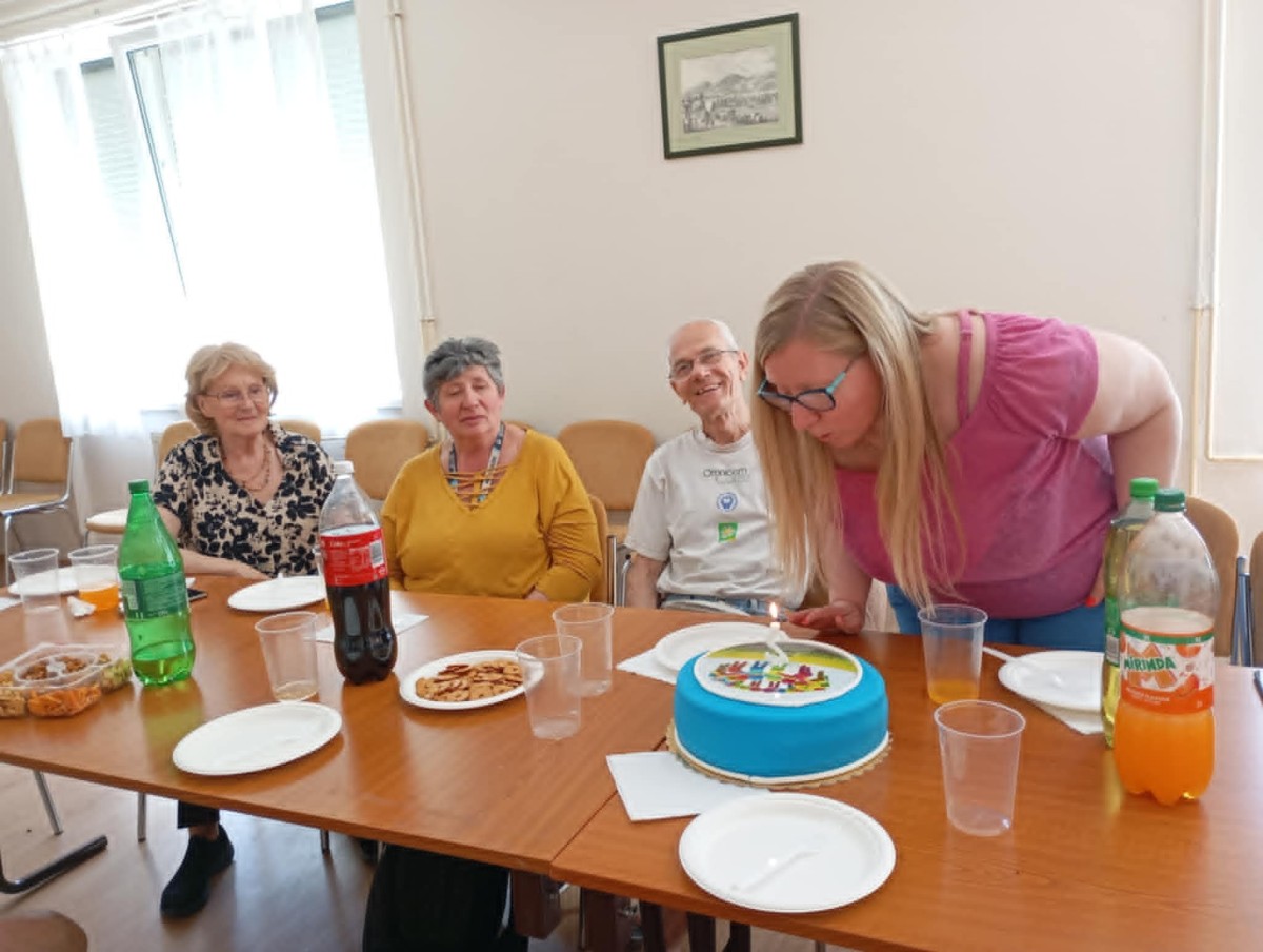 A klubvezető elfújja a szülinapi torta gyertyáját.