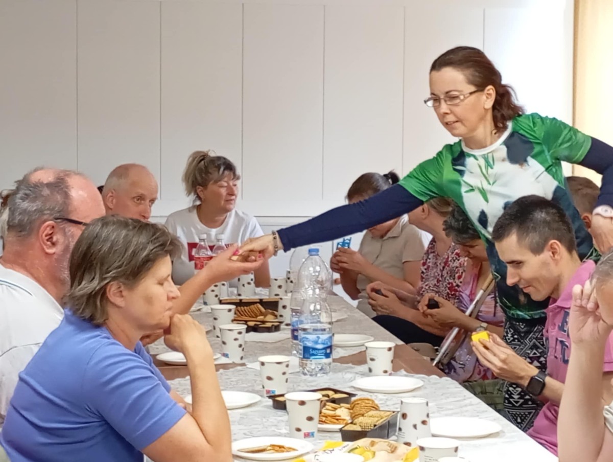 A klubtagok játékalkatrészeket vizsgálnak az asztal körül ülve.