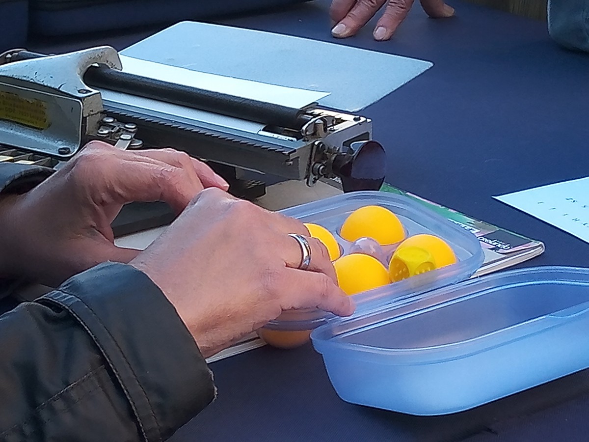 Munkatársunk a Braille-rendszer betűit szemlélteti.