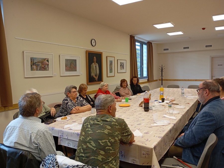 A klubtagok az asztal körül ülnek.