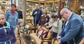 A résztvevők egy régi korhű kávézó faragott támlás székeit nézik.