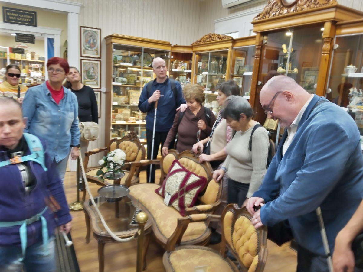 A résztvevők egy régi korhű kávézó faragott támlás székeit nézik.