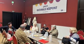 A klubtagok az asztal körül ülnek.