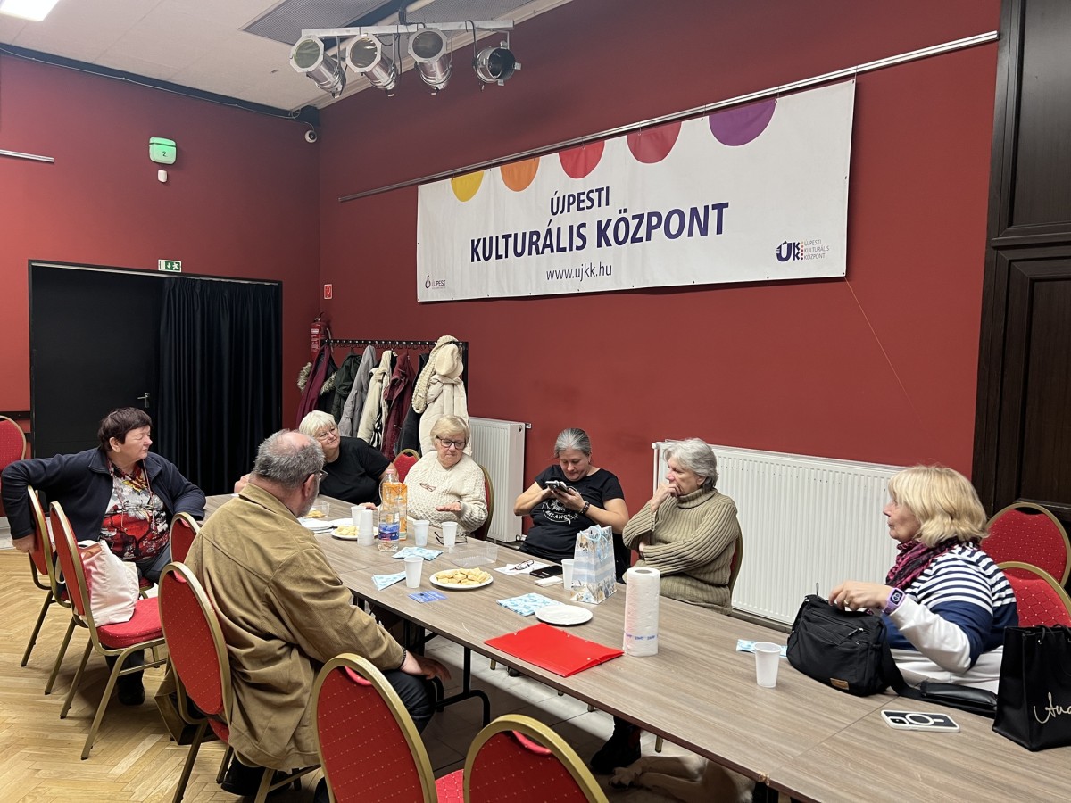 A klubtagok az asztal körül ülnek.