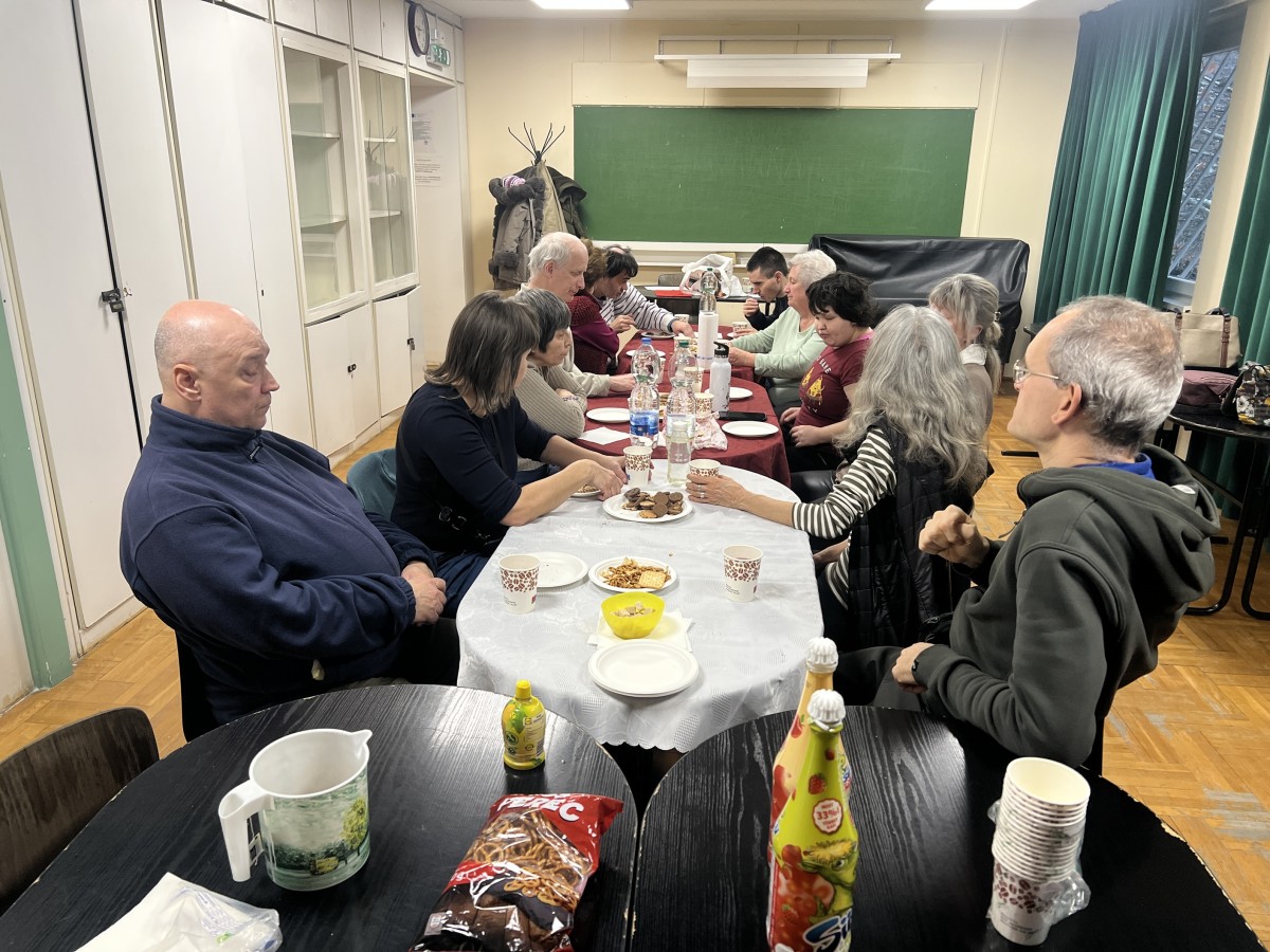 A klubtagok az asztal körül ülnek.