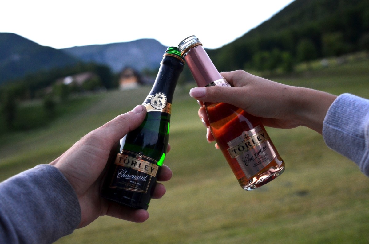 Két férfi keze látszik, mini pezsgős üvegekkel koccintanak.